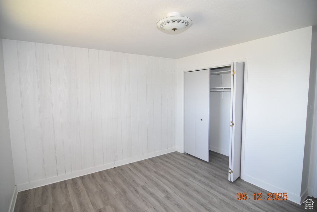 Unfurnished bedroom with wood finished floors and a closet