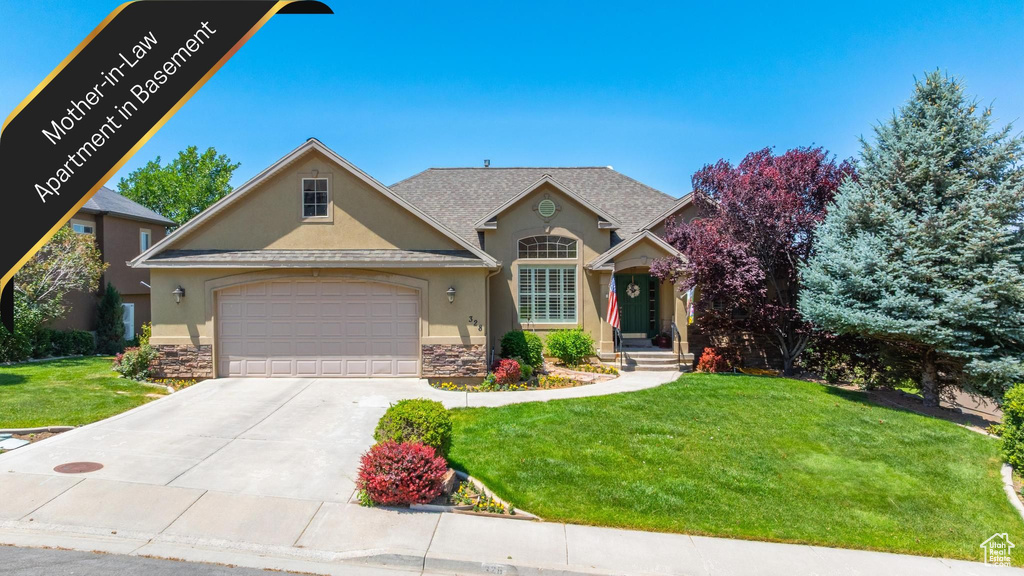 View of front of house with stone siding, stucco siding, a front lawn, and concrete driveway