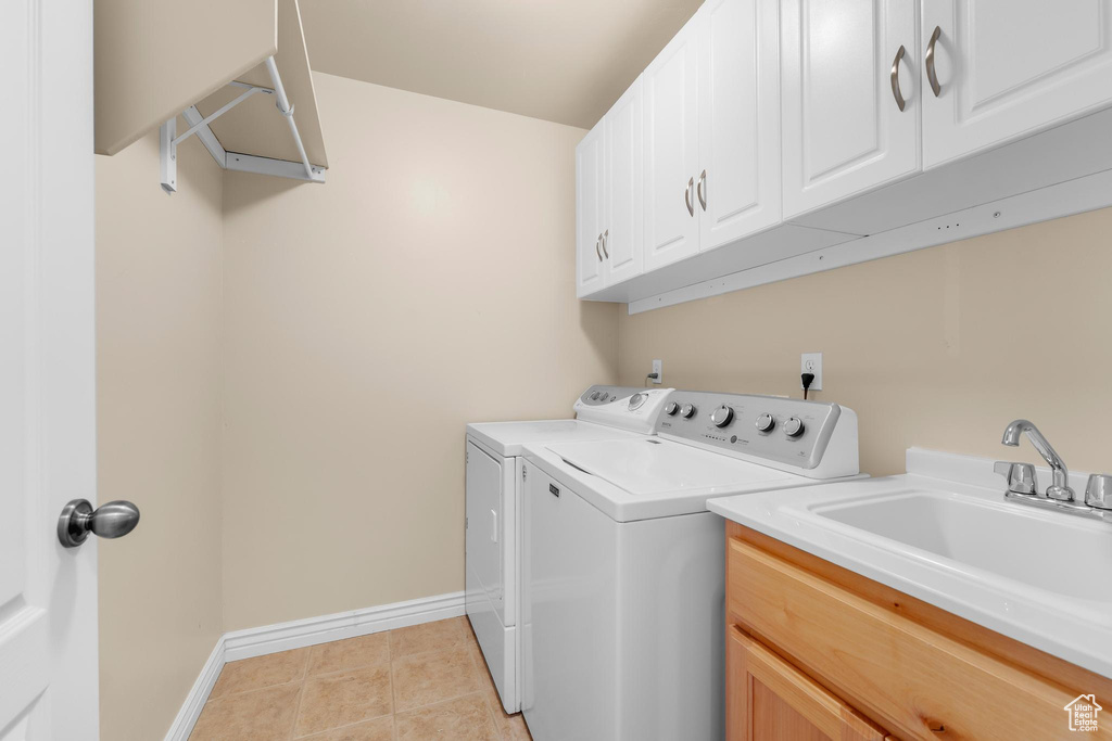Washroom with independent washer and dryer, cabinet space, and light tile patterned flooring