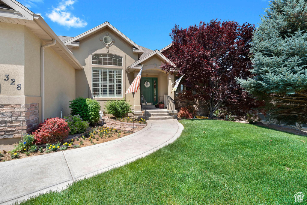 View of front of house with stucco siding, a front lawn, and stone siding