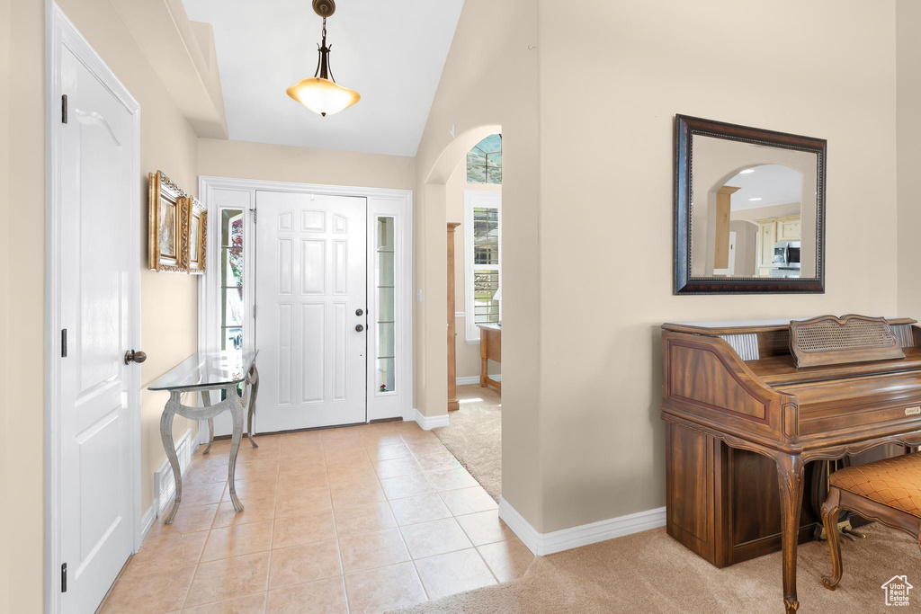 Entryway with arched walkways, lofted ceiling, and light tile patterned floors