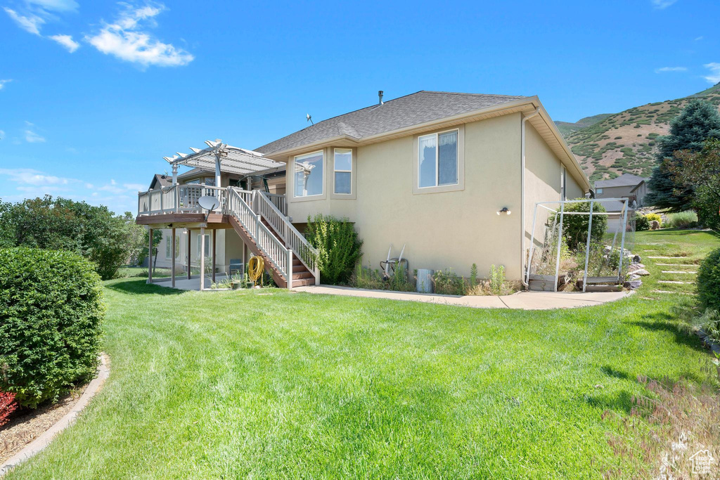 Rear view of house featuring a pergola, stucco siding, stairs, a deck with mountain view, and a yard