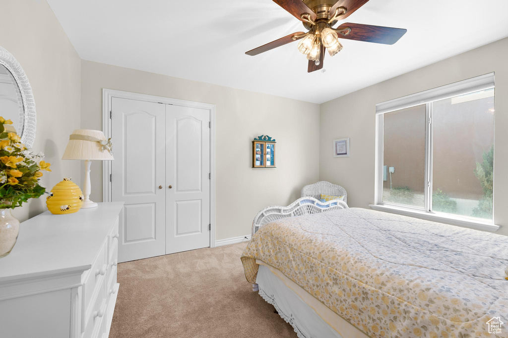 Bedroom with light colored carpet, a closet, and ceiling fan