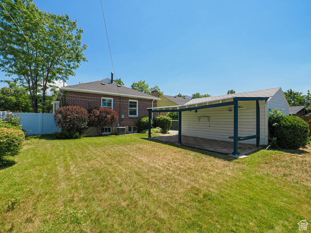 Back of property with brick siding, a carport, and a patio area
