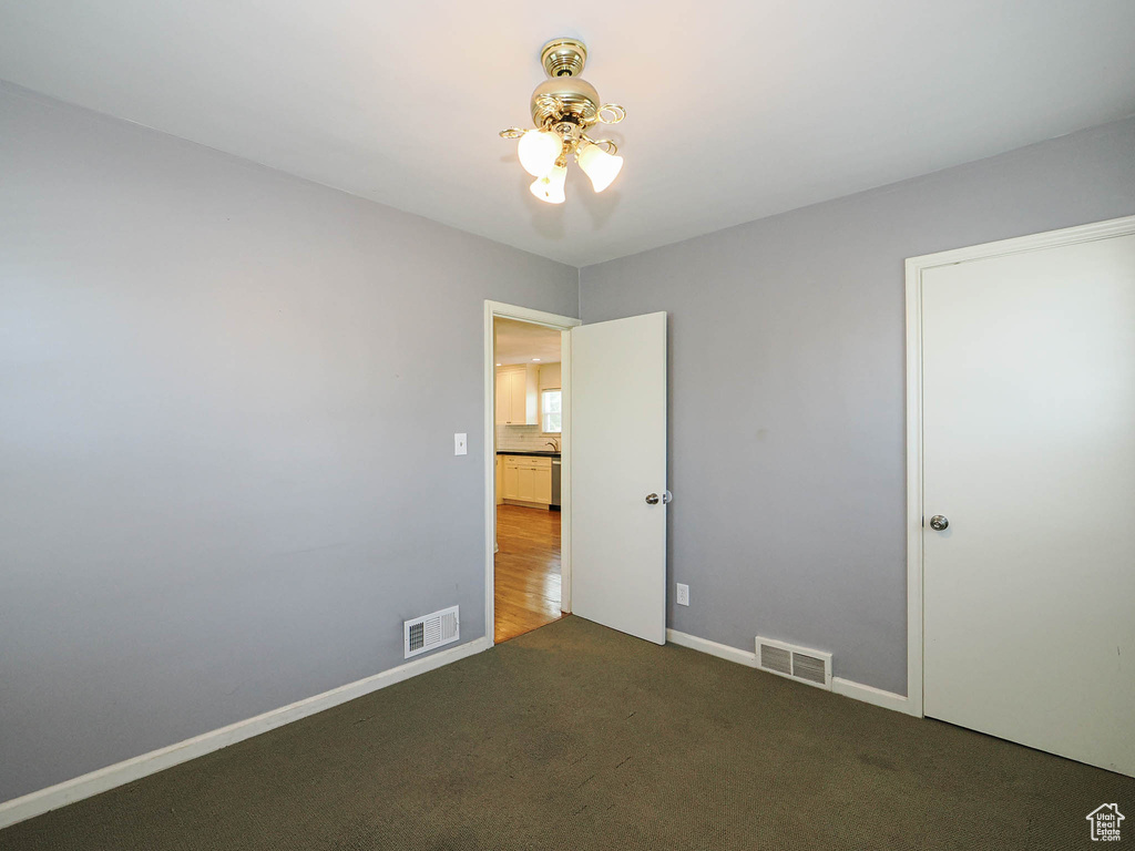 Unfurnished bedroom with dark colored carpet and baseboards
