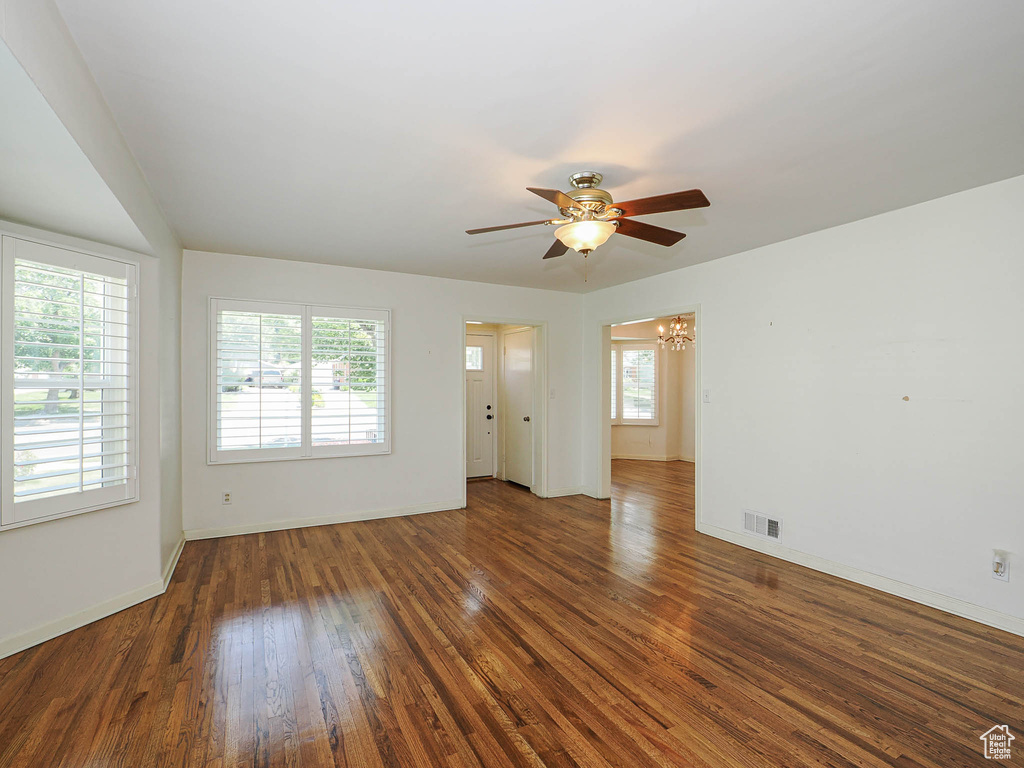 Unfurnished room featuring a chandelier, a ceiling fan, and wood finished floors