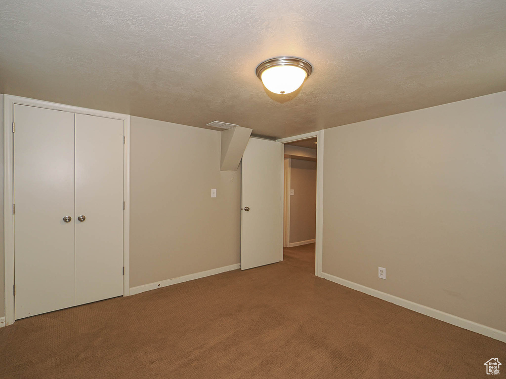 Unfurnished bedroom featuring carpet flooring, a textured ceiling, and a closet