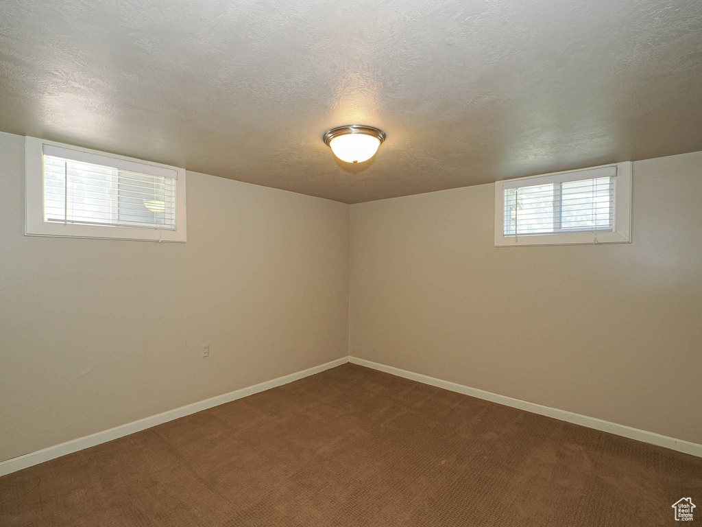 Below grade area featuring a textured ceiling and dark carpet