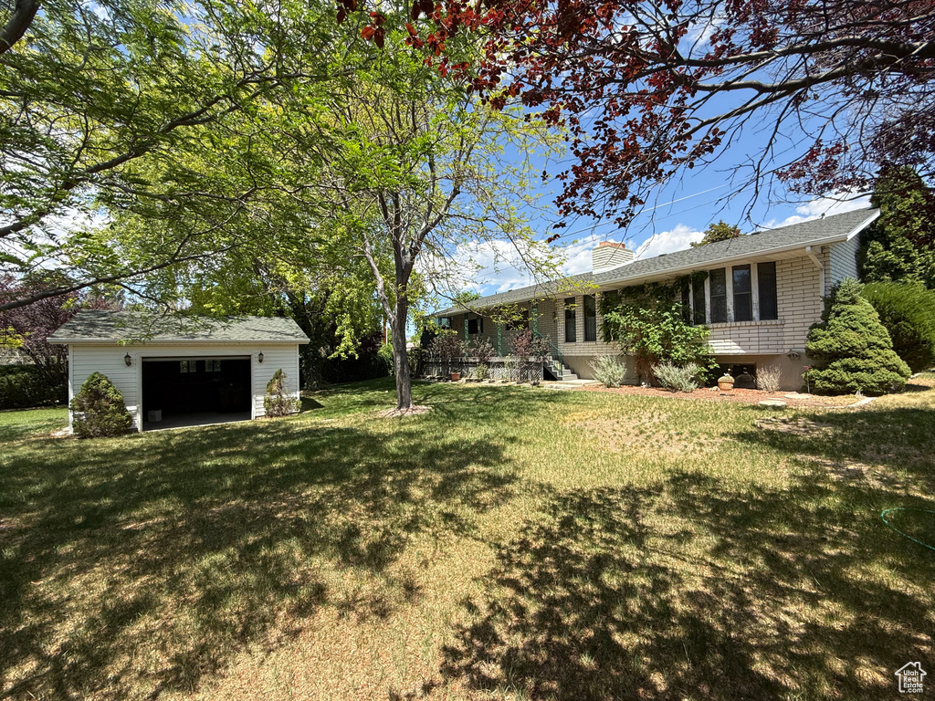 View of grassy yard with an outdoor structure and a garage