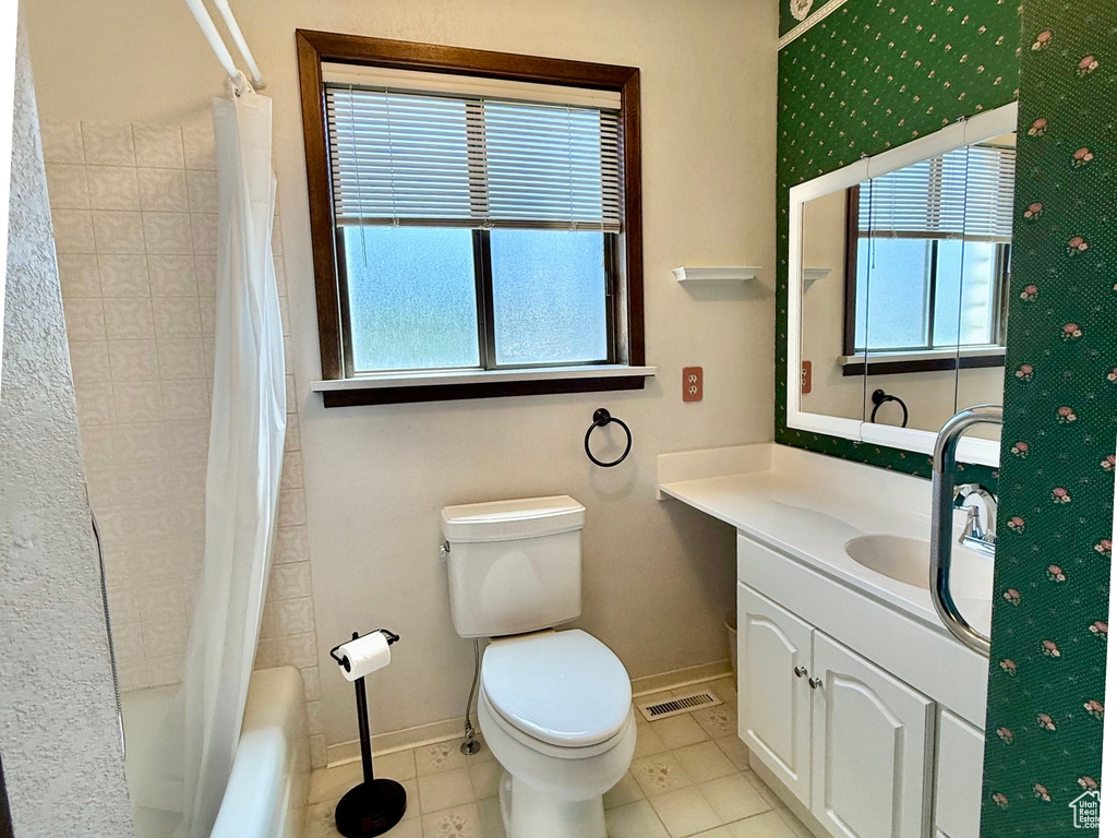Bathroom with healthy amount of natural light, vanity, shower / bath combo, and tile patterned floors
