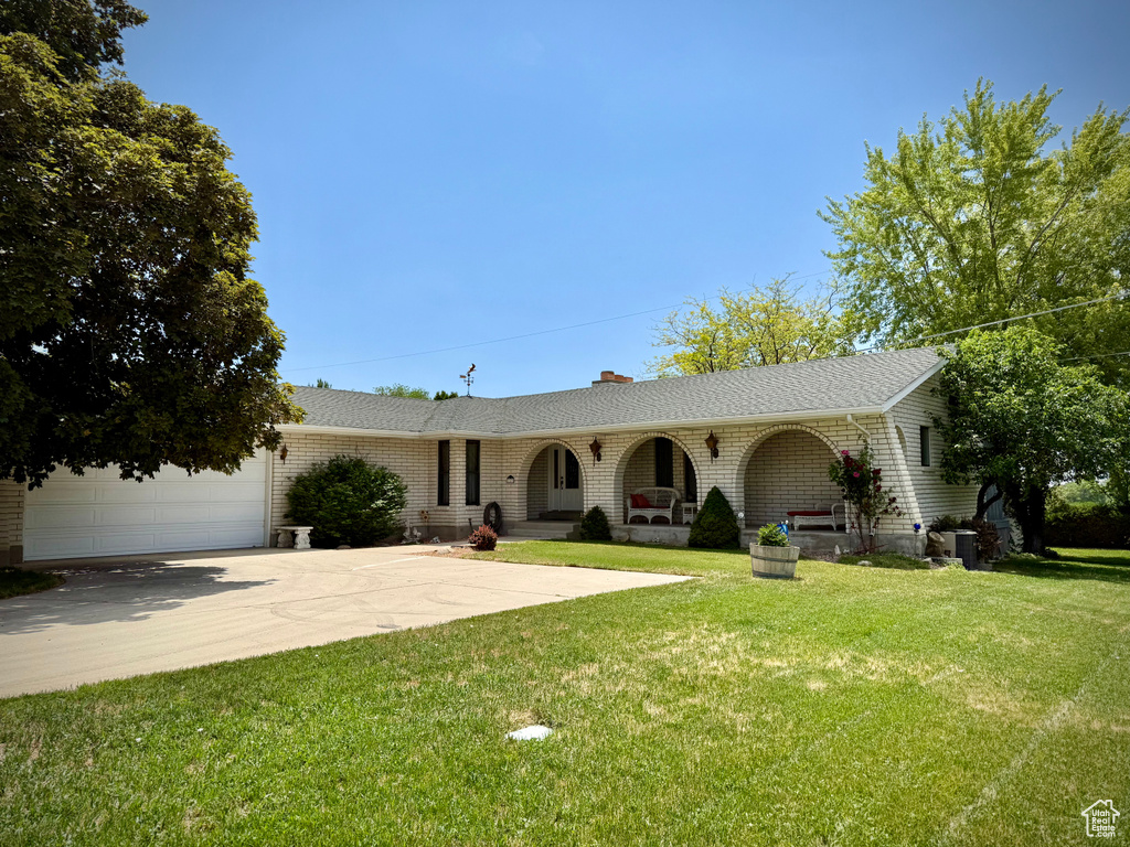 Single story home with driveway, a front lawn, brick siding, a chimney, and an attached garage