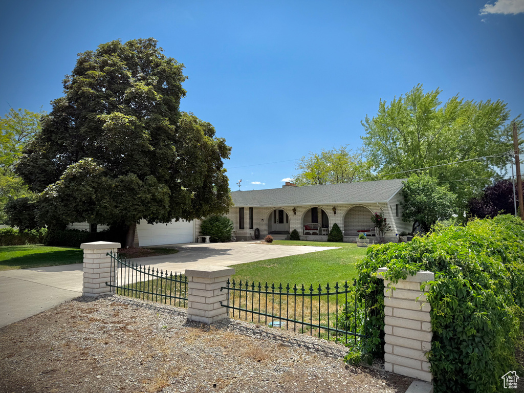 Single story home featuring driveway, a fenced front yard, a garage, and a porch