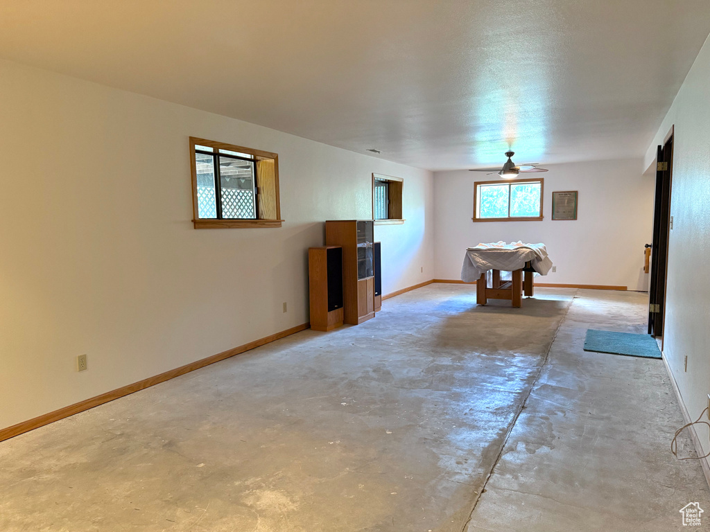 Unfurnished living room featuring concrete flooring, ceiling fan, and billiards table