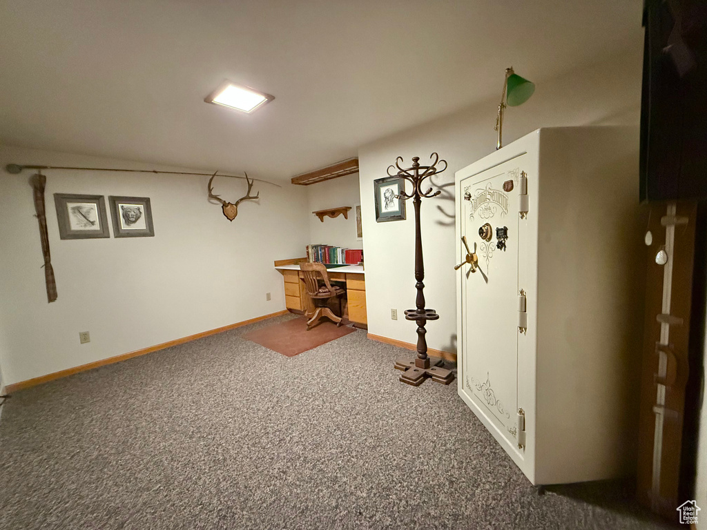 Unfurnished office with dark colored carpet and baseboards