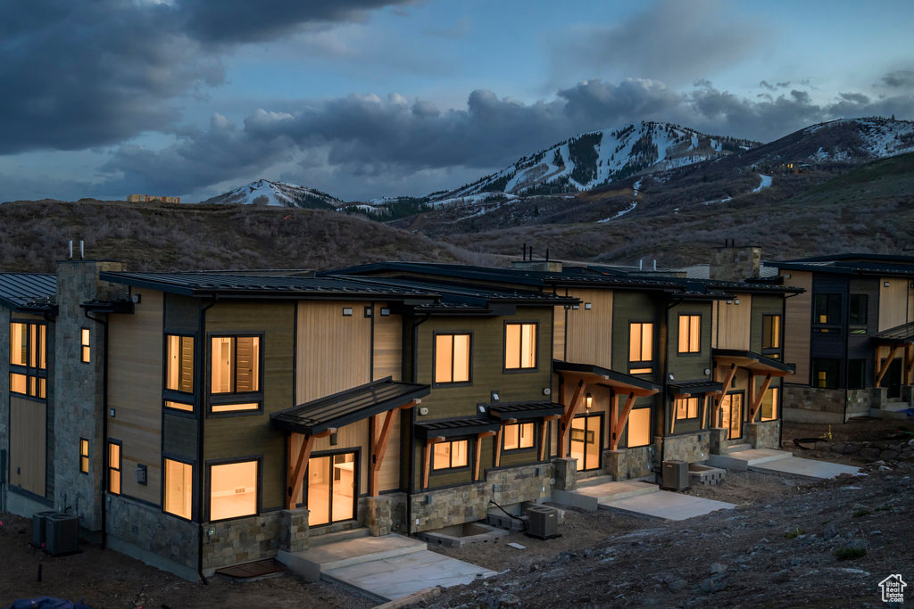 Back of property featuring stone siding, a mountain view, and a metal roof