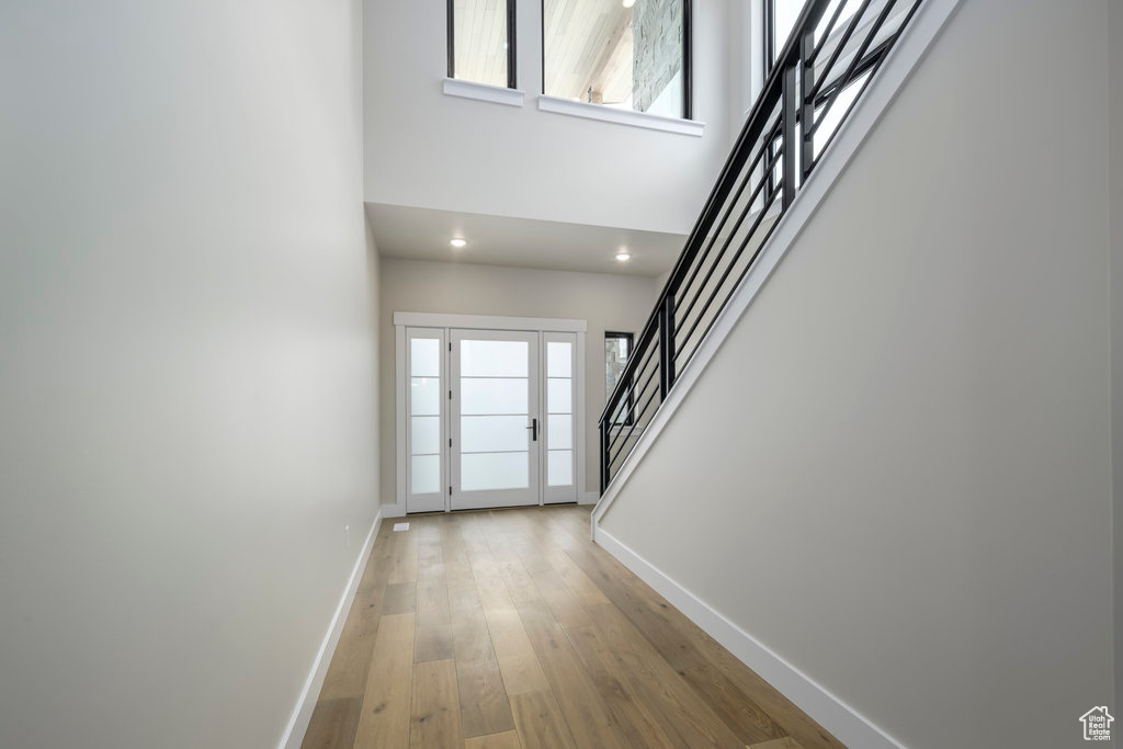 Entryway with baseboards, stairs, a high ceiling, and light wood-style floors