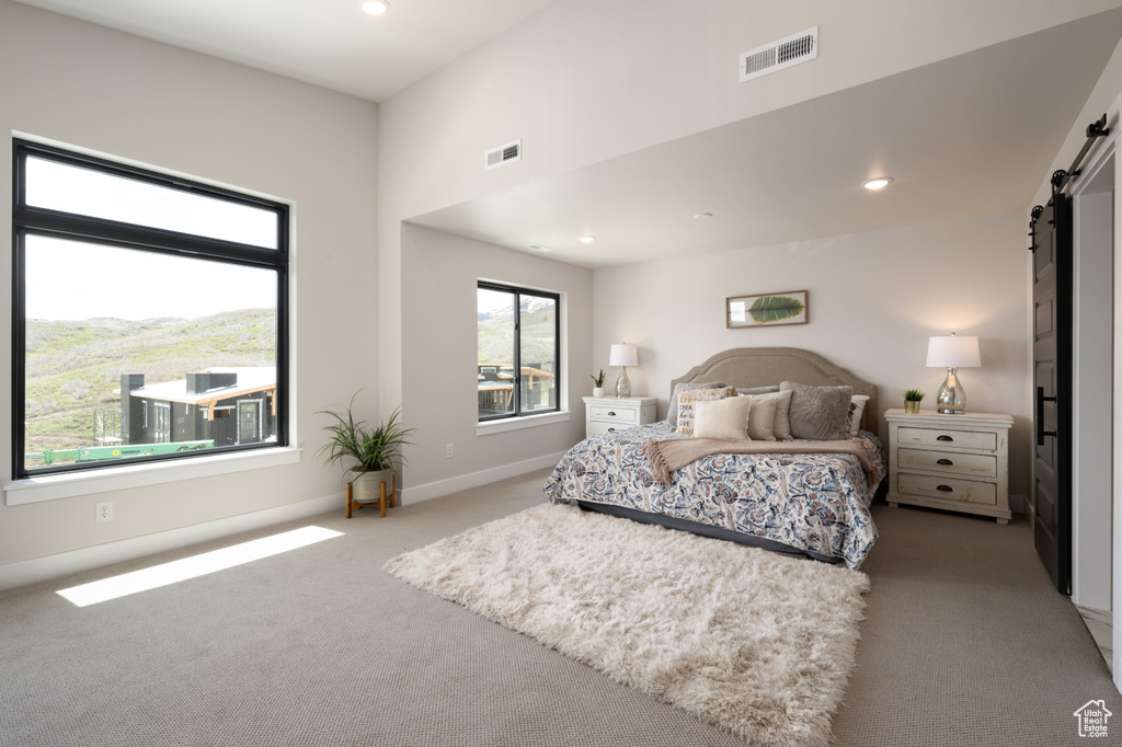 Carpeted bedroom with a barn door, recessed lighting, and baseboards