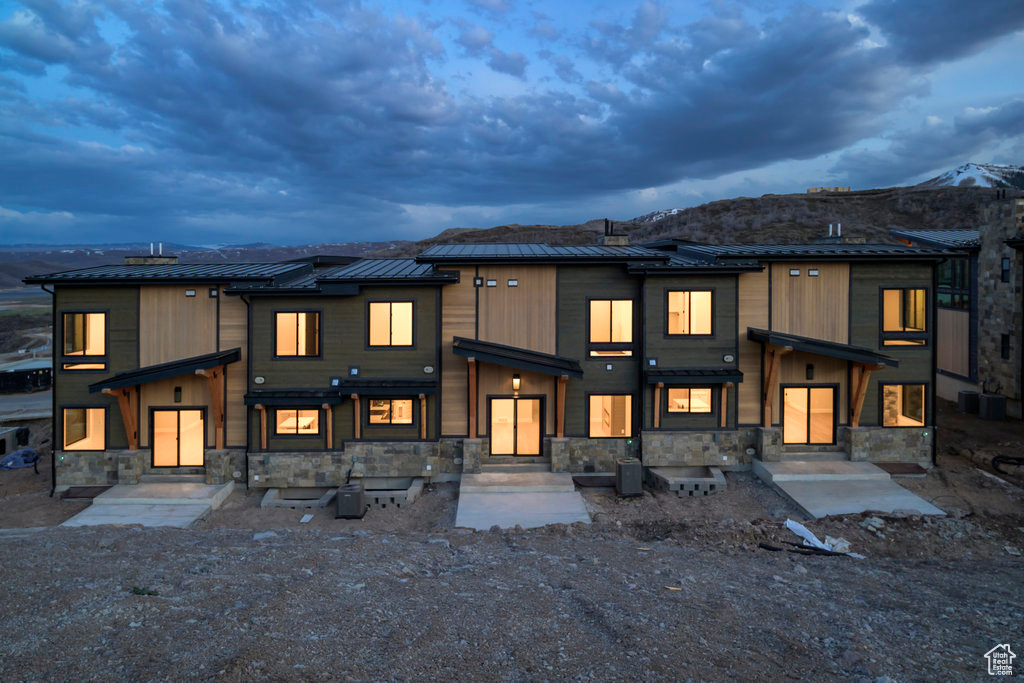 Back of property with a standing seam roof, stone siding, a metal roof, and a mountain view
