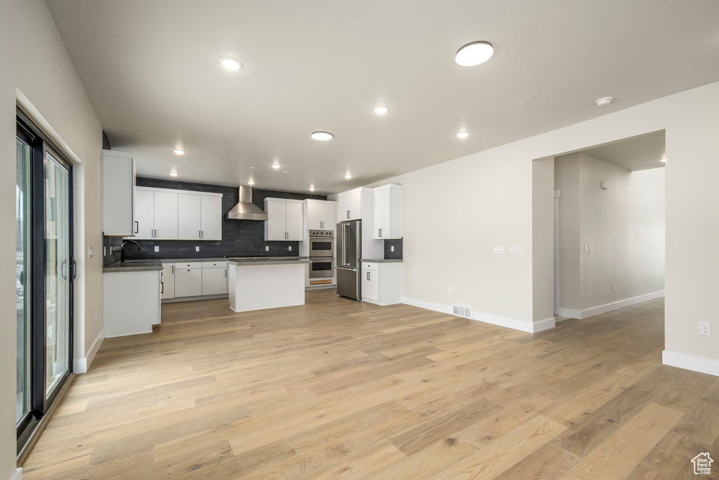 Kitchen featuring stainless steel appliances, backsplash, recessed lighting, light wood finished floors, and white cabinets