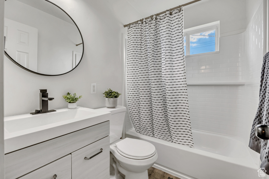 Full bathroom featuring shower / bath combo with shower curtain, vanity, and wood finished floors