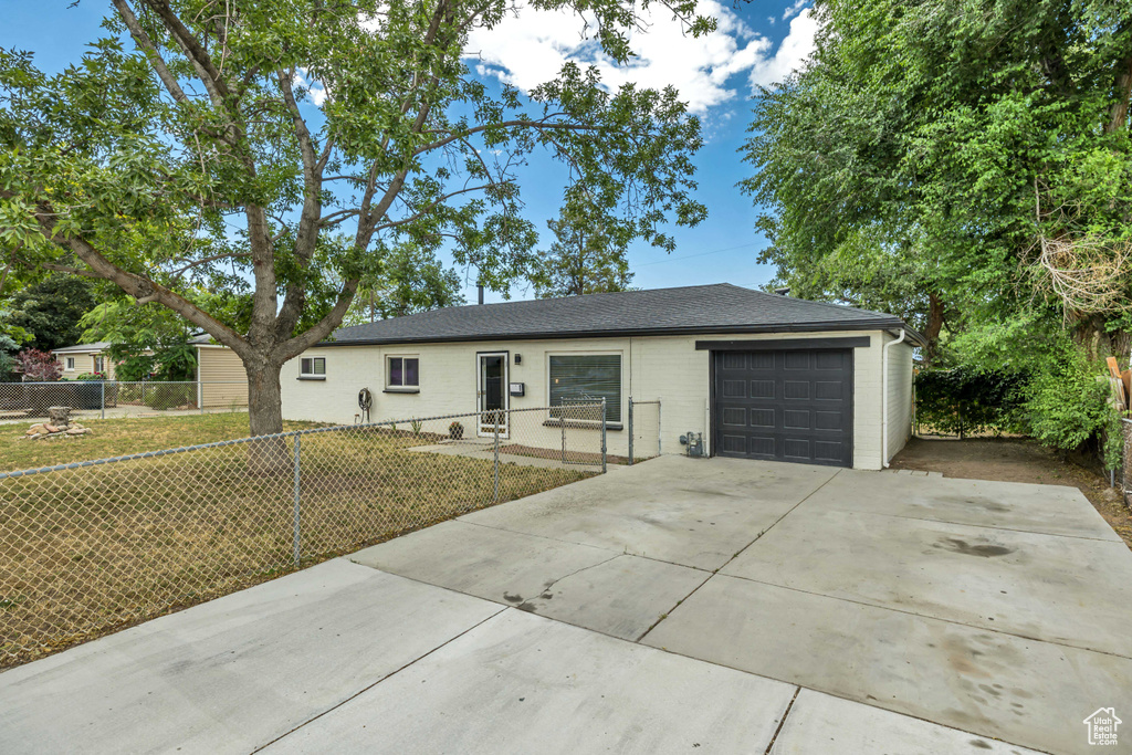 Single story home featuring a garage, concrete driveway, brick siding, and a shingled roof