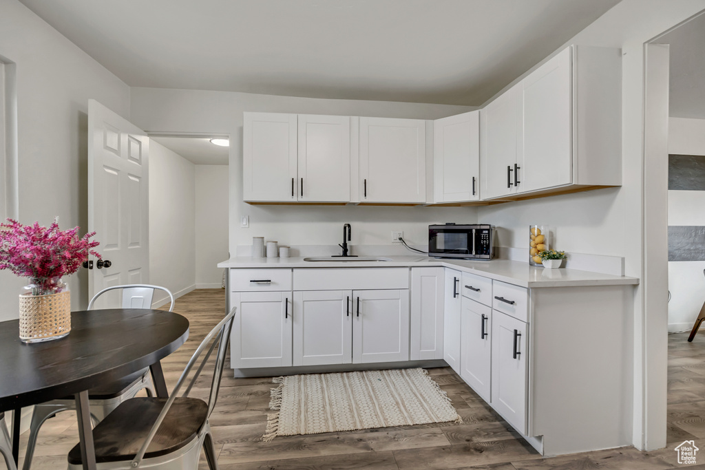 Kitchen with light countertops, wood finished floors, and white cabinetry