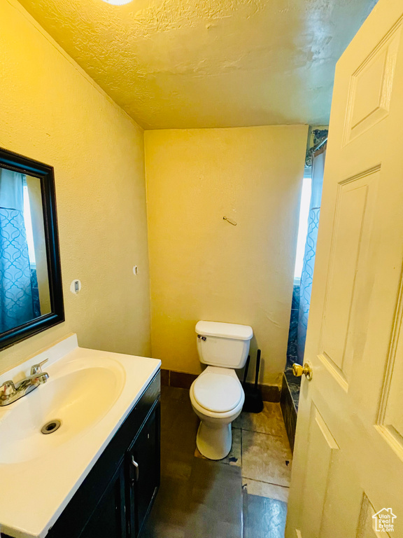 Full bath with vanity, healthy amount of natural light, a shower with curtain, and a textured ceiling