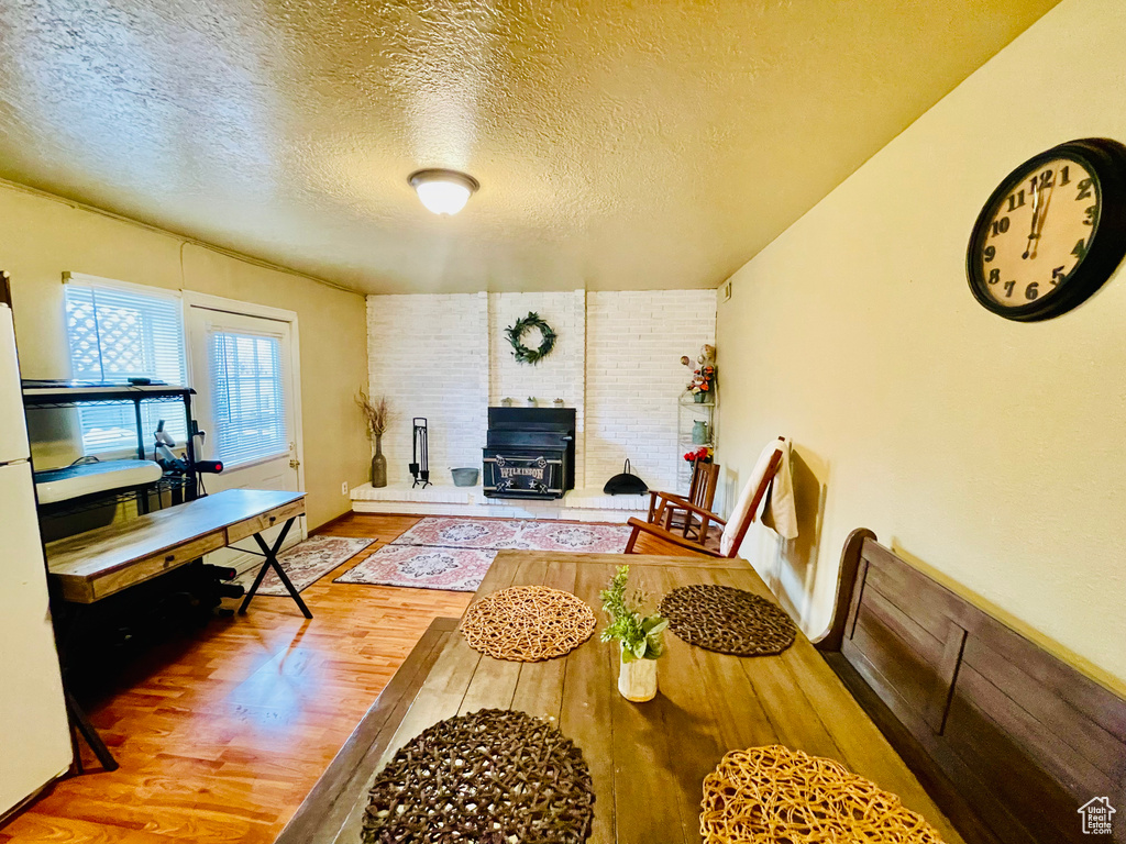 Living area with wood finished floors, a textured ceiling, and a wood stove