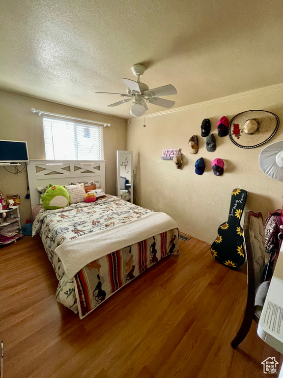 Bedroom with wood finished floors, a textured ceiling, and ceiling fan