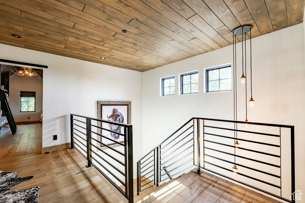 Stairs with wood ceiling, plenty of natural light, hardwood / wood-style floors, and a chandelier