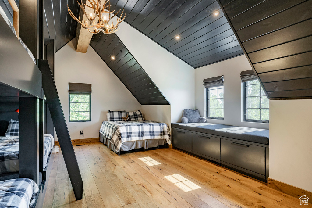 Bedroom featuring a chandelier, vaulted ceiling, light wood-style floors, multiple windows, and wood ceiling