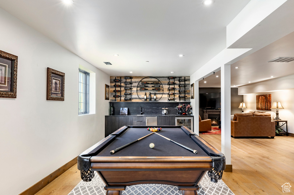 Playroom with a dry bar, wood finished floors, billiards, recessed lighting, and a warm lit fireplace