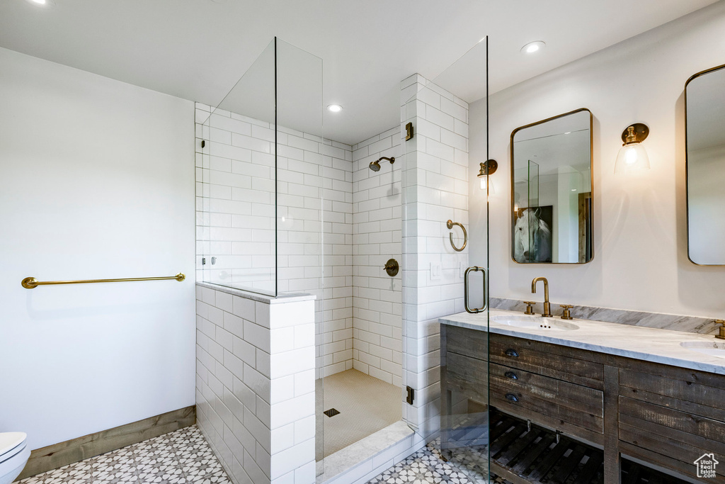 Bathroom with tiled shower, double vanity, and recessed lighting