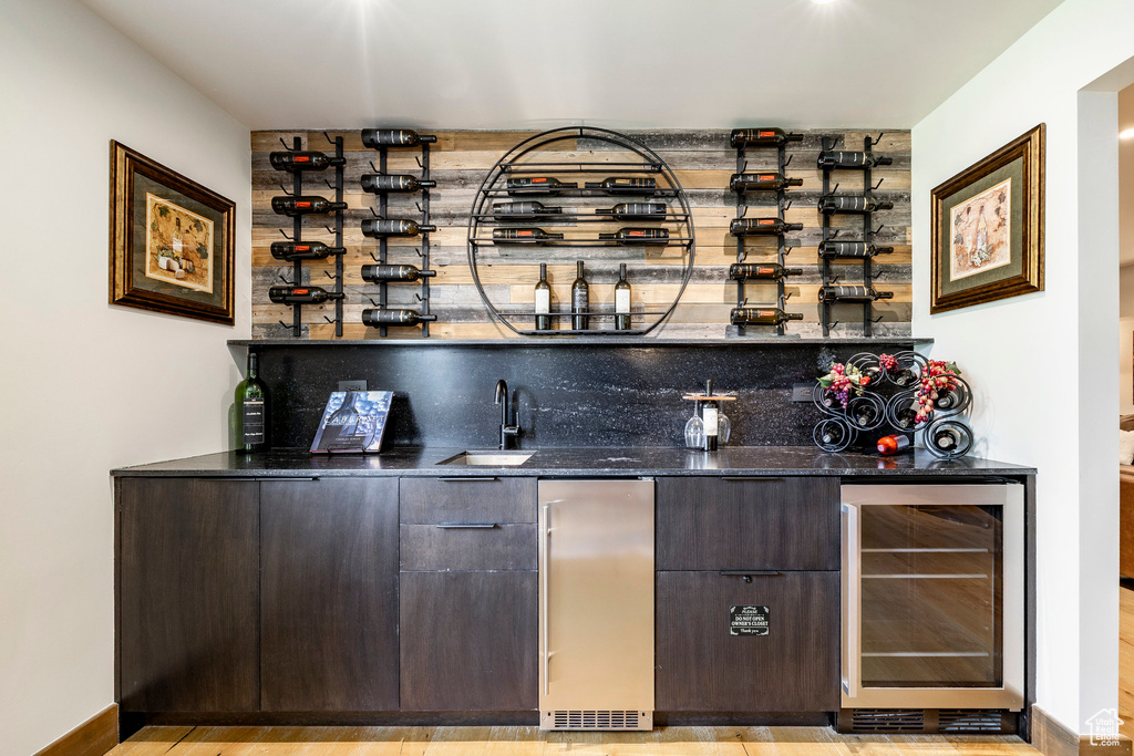 Indoor wet bar with wine cooler, refrigerator, and light wood-type flooring