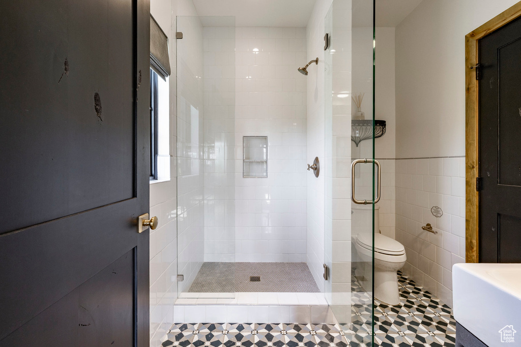 Bathroom featuring a shower stall, tile walls, and tile patterned floors