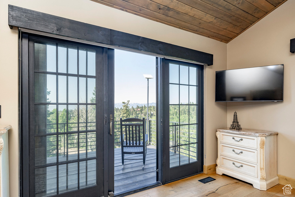 Doorway featuring lofted ceiling, light wood-style floors, wooden ceiling, and plenty of natural light