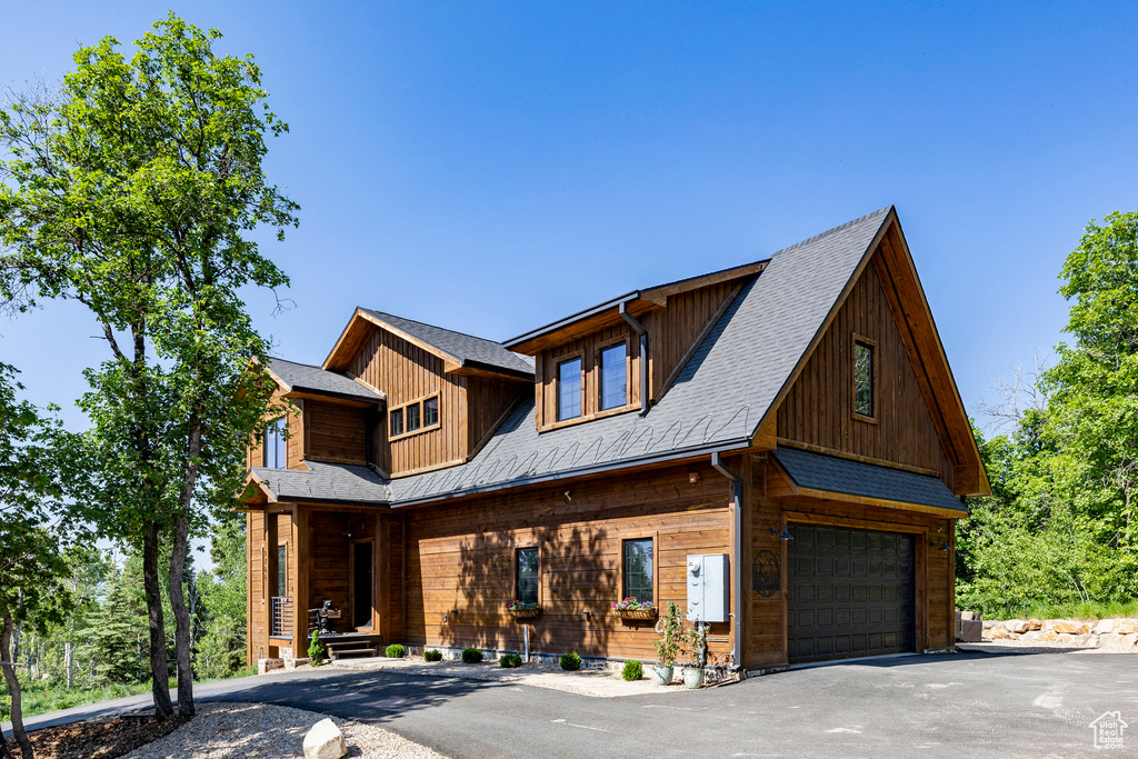 View of front facade featuring an attached garage, covered porch, and asphalt driveway