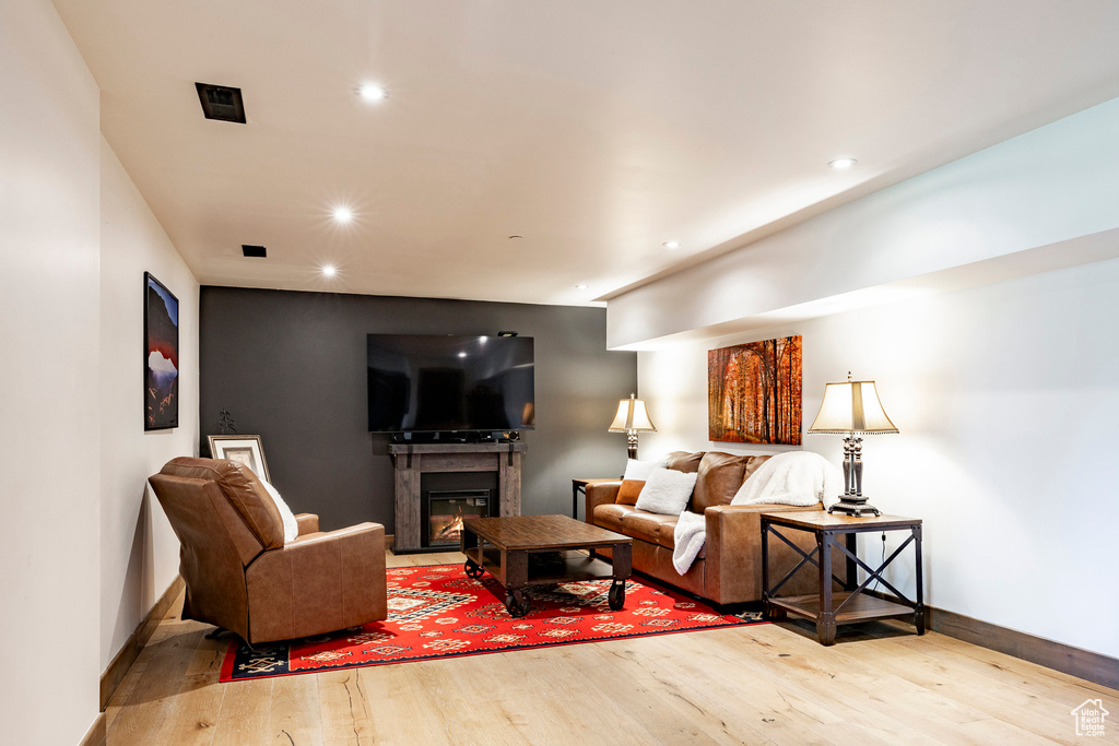 Living area featuring wood finished floors, recessed lighting, and a glass covered fireplace