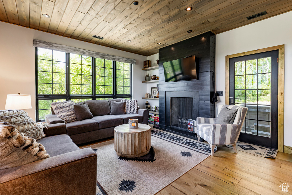 Living room featuring plenty of natural light, wooden ceiling, wood-type flooring, a fireplace, and recessed lighting