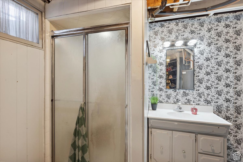 Bathroom featuring wallpapered walls, a stall shower, and vanity
