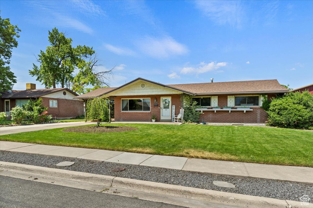 Ranch-style home with a front yard, brick siding, and concrete driveway