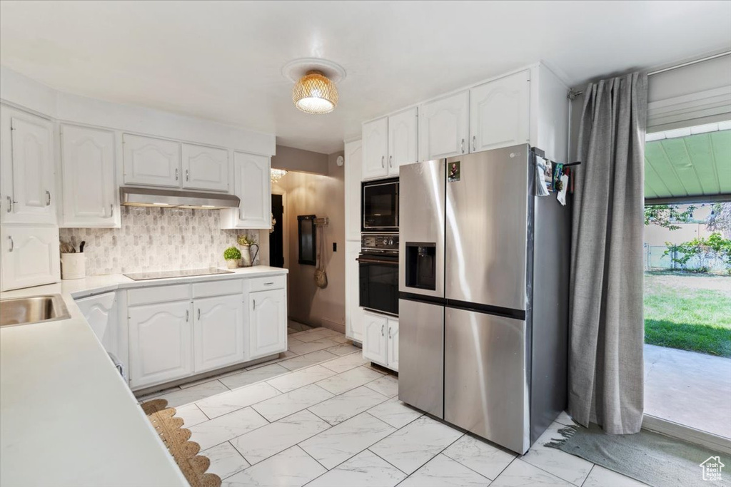 Kitchen featuring black appliances, under cabinet range hood, white cabinets, and light countertops