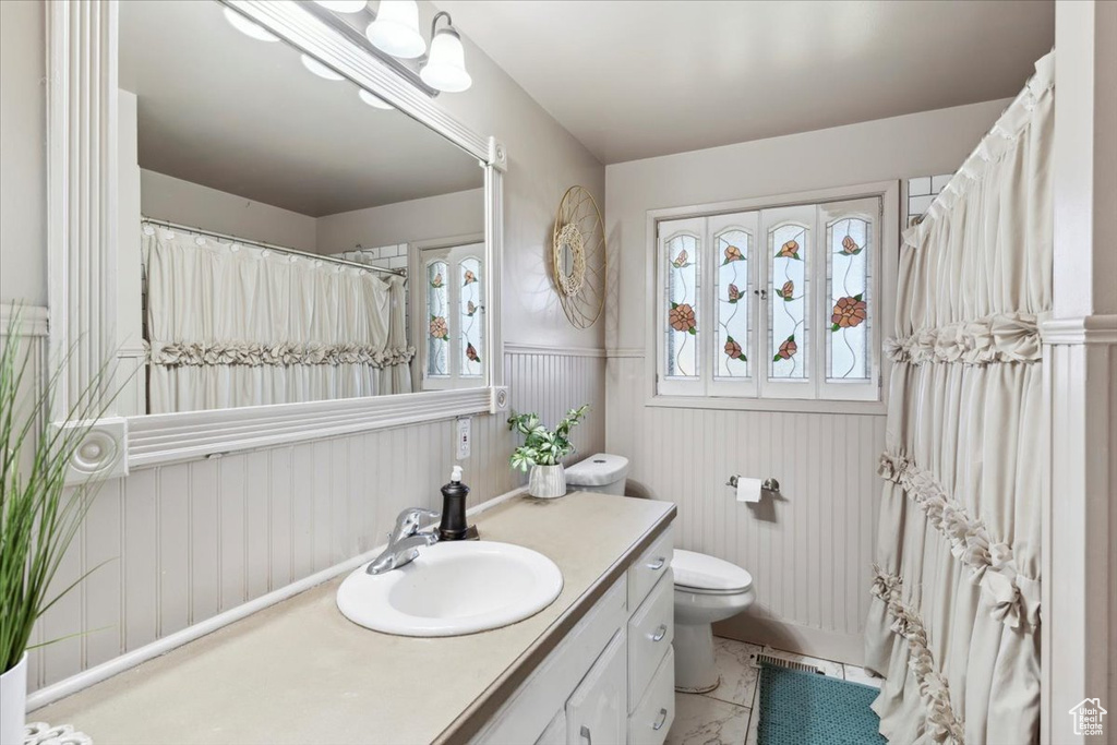 Full bath with vanity and a wainscoted wall