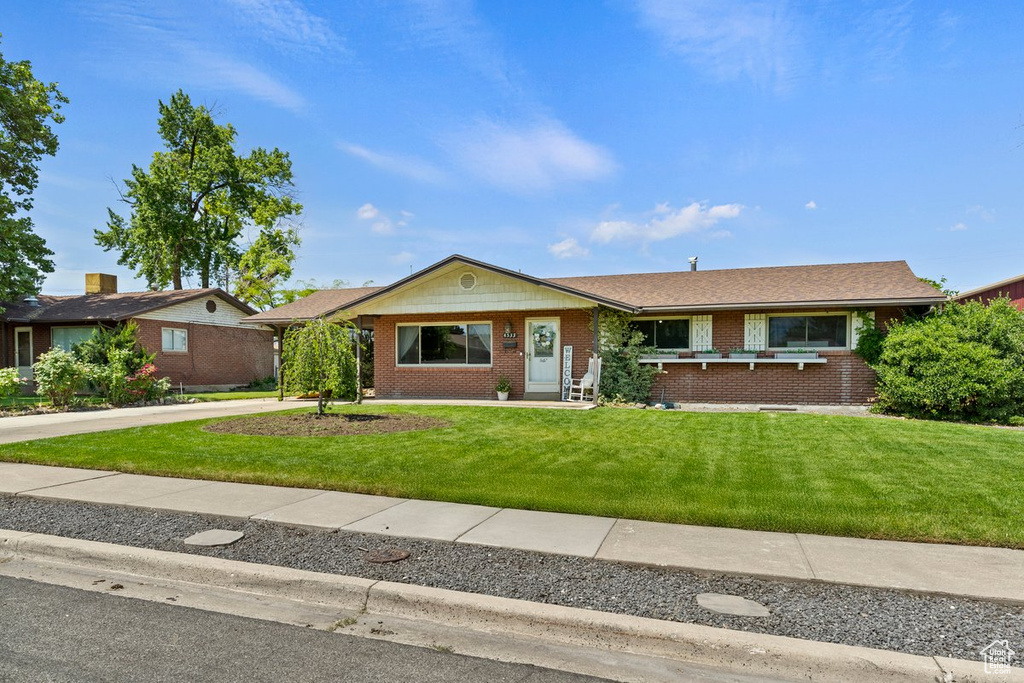 Single story home with a front yard, brick siding, and driveway