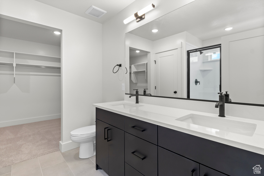 Bathroom with a spacious closet, double vanity, a shower stall, tile patterned floors, and recessed lighting
