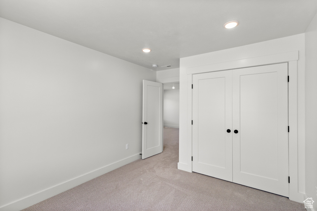 Unfurnished bedroom featuring light colored carpet, recessed lighting, and a closet