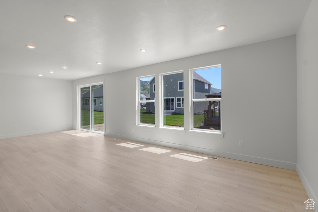 Empty room with light wood finished floors and recessed lighting