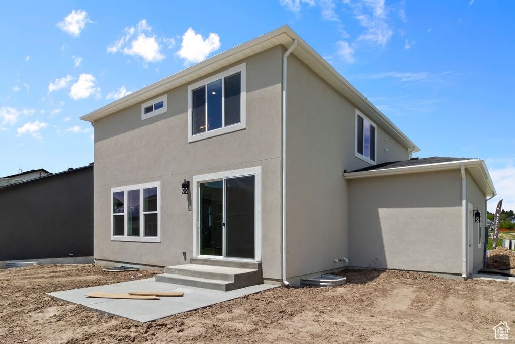 Rear view of property featuring stucco siding and entry steps