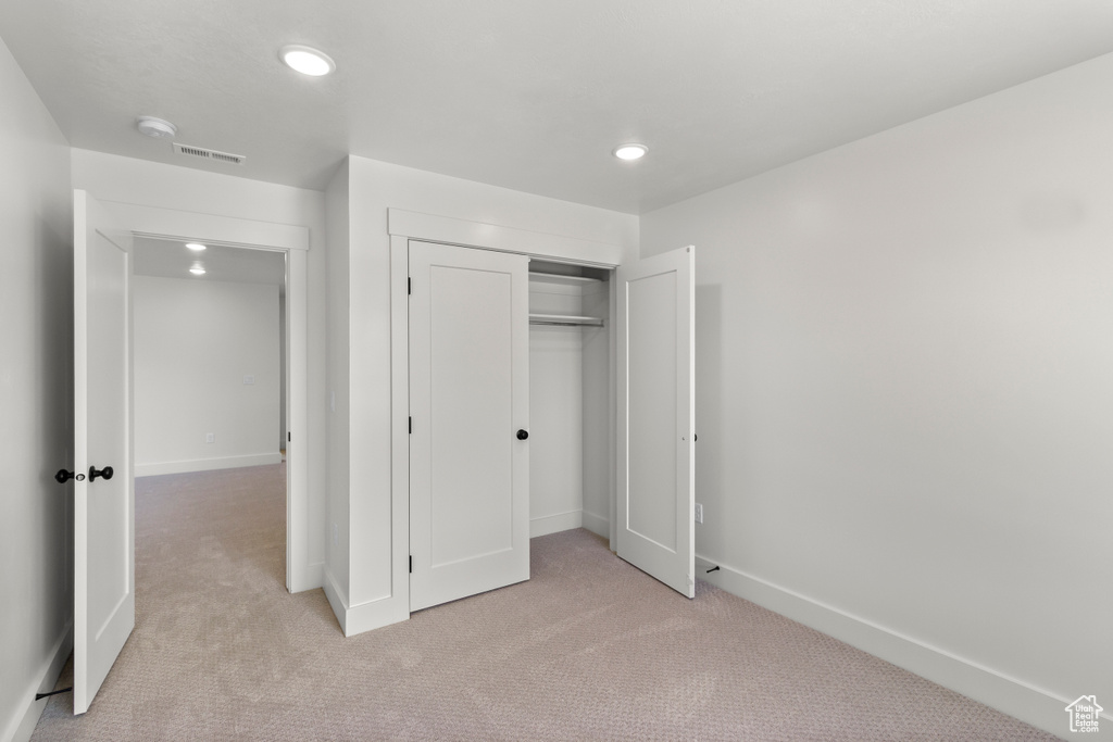 Unfurnished bedroom with light colored carpet, recessed lighting, and a closet
