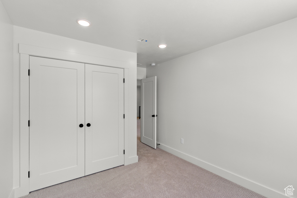 Unfurnished bedroom with light carpet, a closet, and recessed lighting